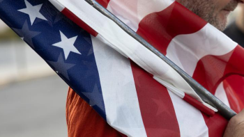 Volunteer in red shirt carrying U.S. flag.