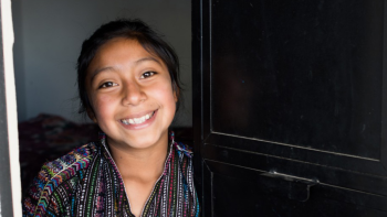 Guatemalan girl smiling in her doorway.