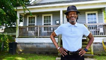 A man smiles as he stands proudly in front of his Habitat home in New Orleans.