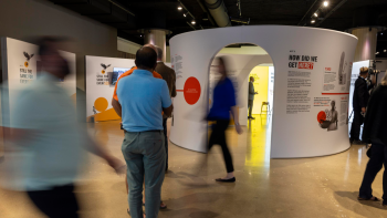 People walking around and reading displays in an interactive exhibit set up in an open area 