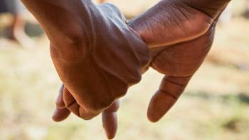 Close up of two people holding hands.