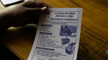 hand resting on desk with flyer