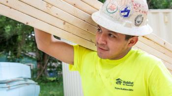 Home builder with hard hat holding wood