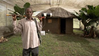 Kenyan man in front of home with banana trees