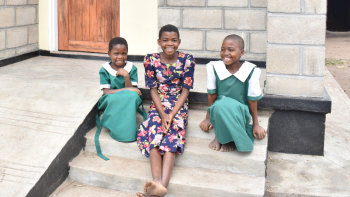 Three Malawian girls in dresses smiling together