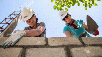 Brenda Fisher and Melissa Corbett (blue shirt) work on a concrete block wall during a Global Village build in Bajos De Chila, Oaxaca, Mexico.