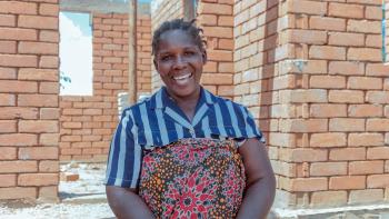 A lady standing in front of a house under construction