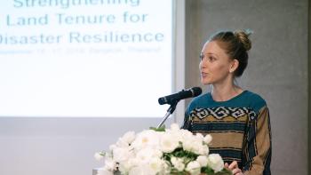 Anna, a cohort, speaks at a podium in front of a projected slideshow.