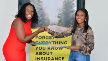 Two women bump fists in front of insurance poster