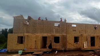 Wide shot of Habitat build site with Team Depot volunteers working on framing multiple houses