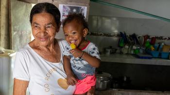 PHOTO. CARTAGENA, COLOMBIA. Isabel María arrived in the Olaya Herrera neighborhood in Cartagena 33 years ago after being displaced by violence. Through her own effort she acquired her home and, after separating, took on the upbringing of her two children and two grandchildren. Today she feels at peace seeing her grandson crawl safely on the new concrete floor installed thanks to 100 Thousand Floors to Play. © Habitat for Humanity International / David Estrada