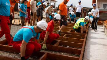 Volunteers lifting a wall from the ground on build site