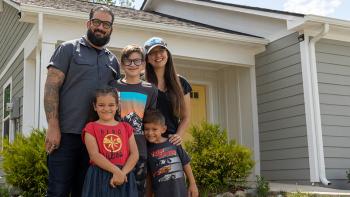 Family of five smiling in front of their Habitat home