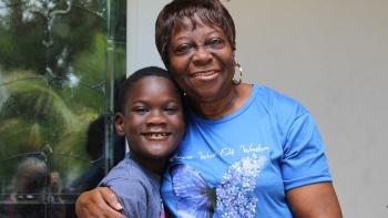 A woman hugs her grandson outside a home.