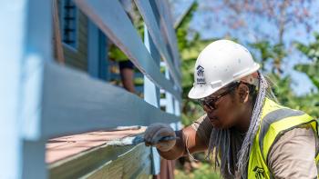 Fijian community member painting floor of a porch