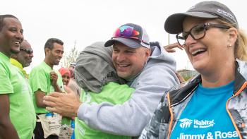 Garth and Trish walking through a crowd of volunteers, Garth is hugging a volunteer.