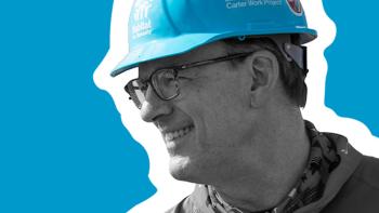 Black and white photo of Jonathan Reckford smiling, wearing a blue hard hat. He is outlined in white on a blue background.