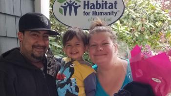 Jennifer posing in front of Habitat house with family