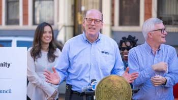 Habitat CEO Jonathan Reckford speaking at a lectern displaying the seal of the city of New York. Several other speakers at the ceremony stand behind him.