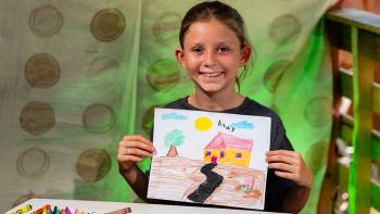 Una niña muestra el dibujo de su casa