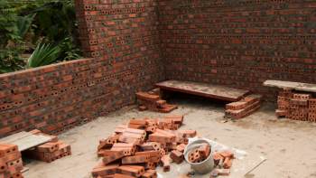 Partially built brick wall with a logo lockup of Habitat for Humanity and Symbiotics.