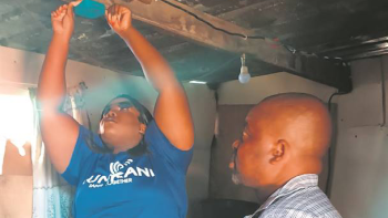 Woman installing a smoke detector as a man watches