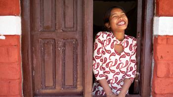 A woman smiling in a window.