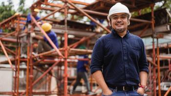 Man in hard hat standing in front of scaffolding on construction site