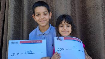 Children smiling holding a sign