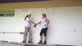 Two volunteers shaking hands on a construction site in hard hats