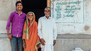 Smiling homeowners standing by doorway