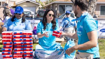 A volunteer hands off a first-aid kit to another volunteer as they pack emergency kits.