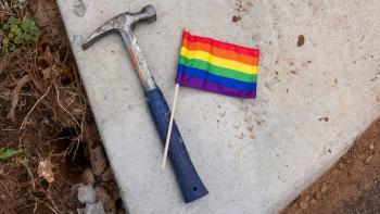 A hammer and a small pride flag laying side-by-side.
