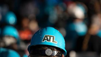 Back of a volunteer's head wearing a blue hard hat with an "ATL" sticker on it.