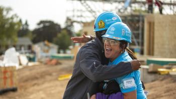 man and woman volunteer hugging at built site
