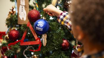 Young boy hanging a Habitat for Humanity ornament on a Christmas tree.