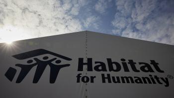 Dark blue Habitat logo on a white building with a blue sky and clouds behind it.