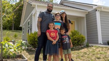 Neil, Erica and their three kids hugging outside their home.