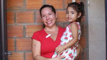 Madre sonríe mientras sostiene a su hija pequeña en el baño de su hogar, un espacio seguro y digno que refleja bienestar y nuevas oportunidades para la familia