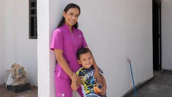Una madre con su hijo frente a una casa