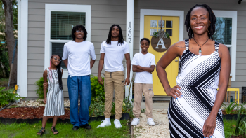 Smiling family of five standing in front of their new home