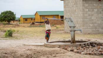 A young boy pumps water at a water kiosk.