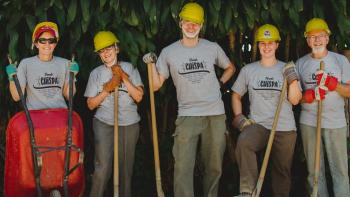 Group of volunteers in hardhats holding shovels