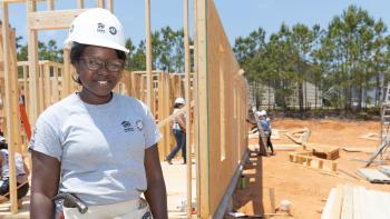AmeriCorps member Imani standing on a build site with hard hat.