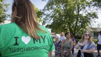 Woman in 'I love my neighborhood shirt' gathers with fellow community members.