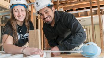 Young woman and young man smiling while working on a Collegiate Challenge build.