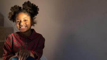 young blacks girl sitting on the stairs of her home, smiling