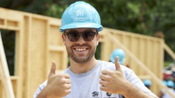 AmeriCorps member on build site gives two thumbs up