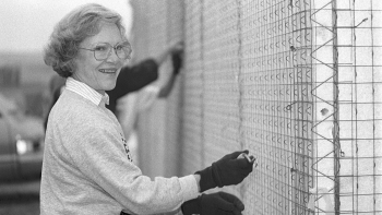 Black and white photo from 1990 of Rosalynn Carter smiling while working on the build site 