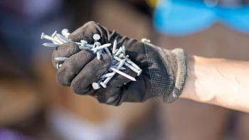 Close-up of gloved hand holding a handful of nails